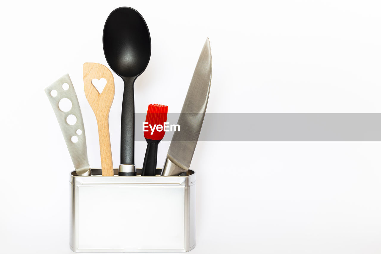 Close-up of utensils in container on white background