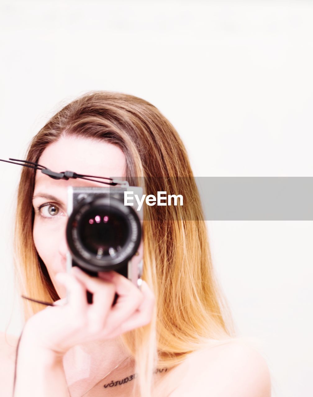 Portrait of woman photographing against white background