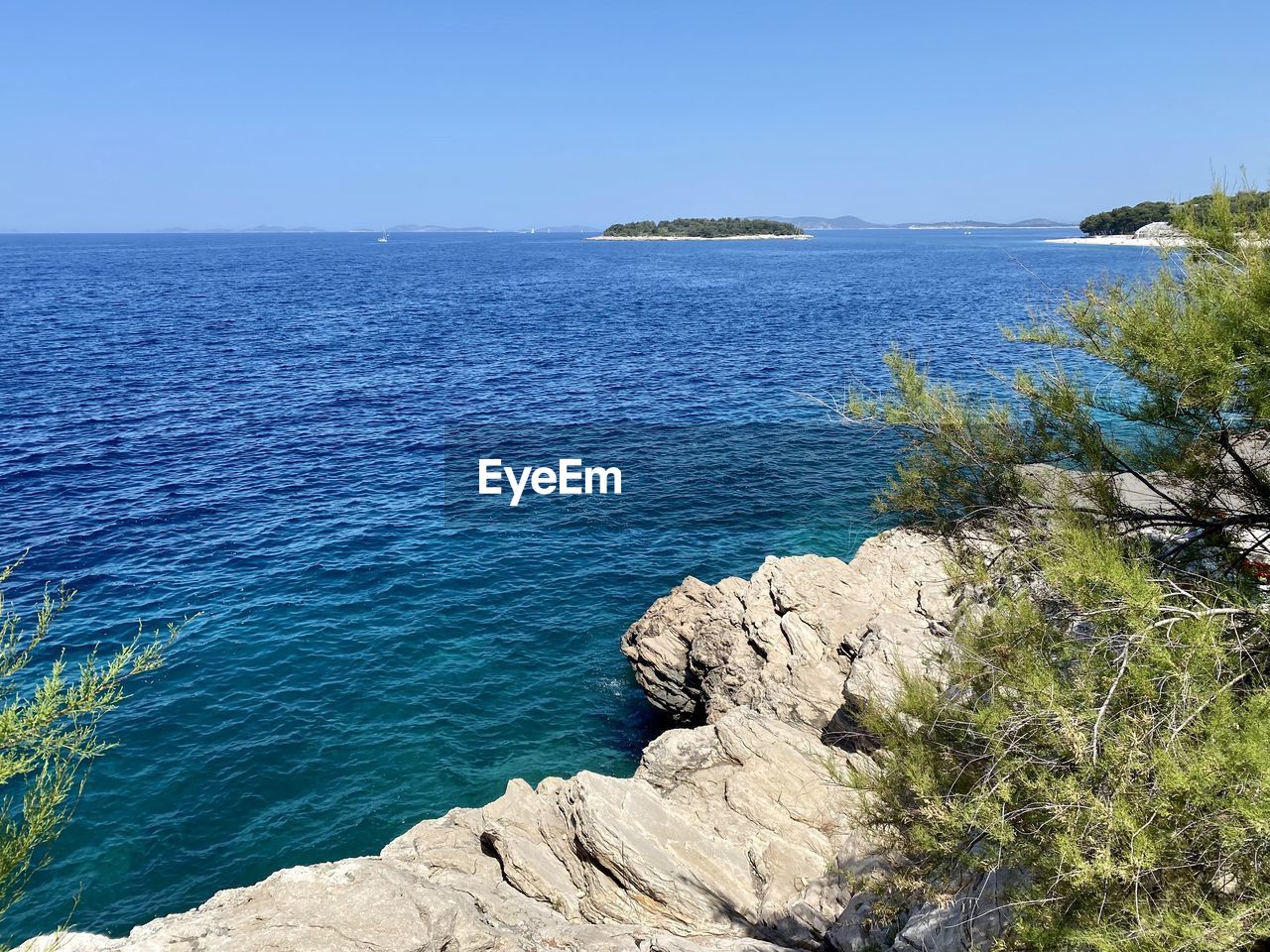 water, sea, scenics - nature, sky, beauty in nature, land, nature, beach, blue, coast, tranquility, cliff, shore, clear sky, rock, tranquil scene, travel destinations, vacation, ocean, travel, body of water, day, no people, terrain, plant, cove, horizon over water, bay, horizon, coastline, sunny, outdoors, tourism, idyllic, landscape, tree, environment, non-urban scene, sunlight, islet, trip, holiday