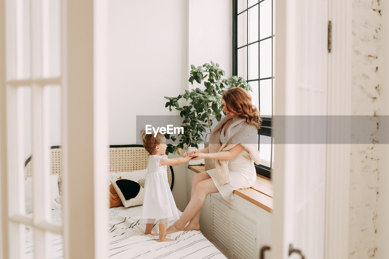 Happy mom and little daughter baby relax unwind and play in a cozy room in a cozy house