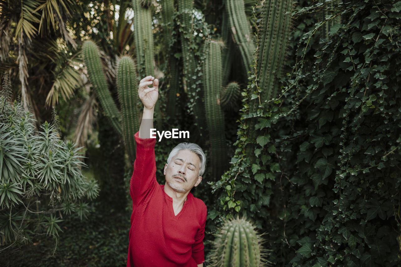 Mature man stretching amidst plants in garden