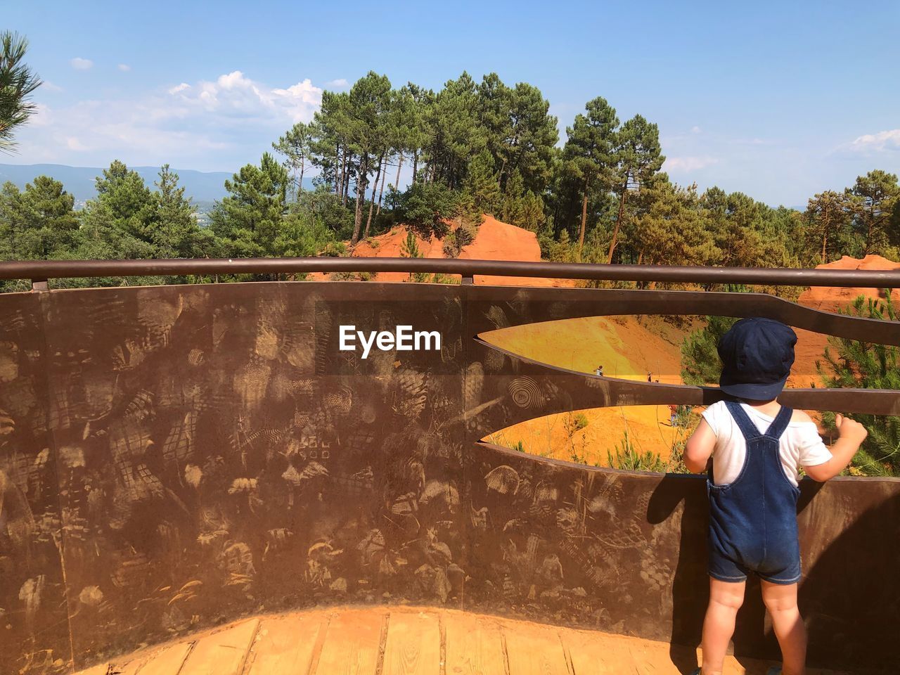 Rear view of baby boy standing against railing