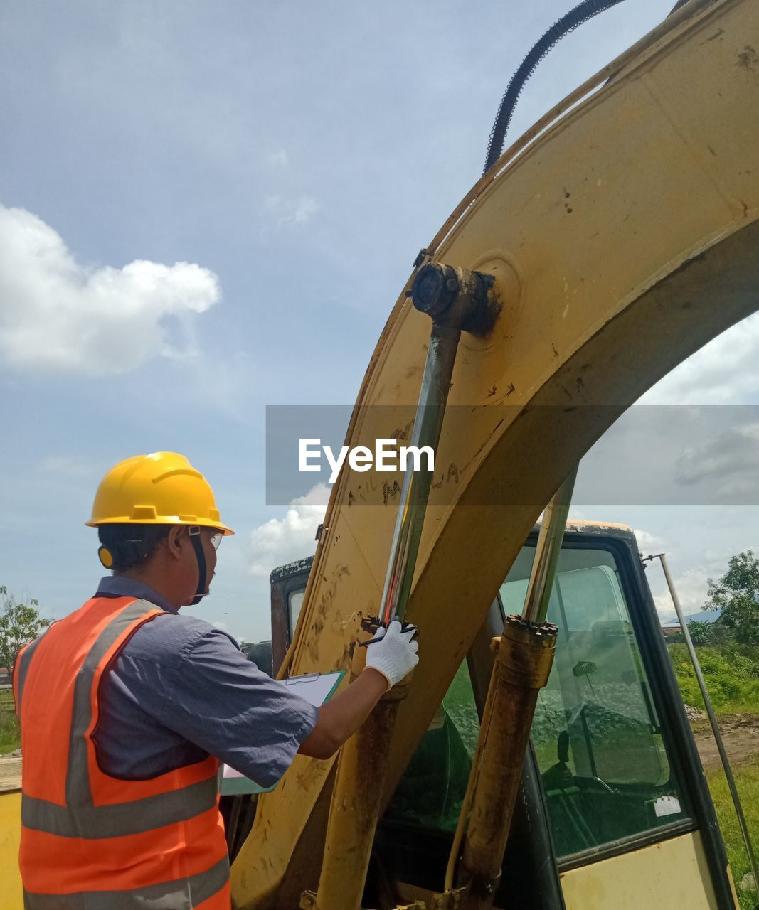 LOW ANGLE VIEW OF MAN WORKING ON YELLOW BRIDGE AGAINST SKY