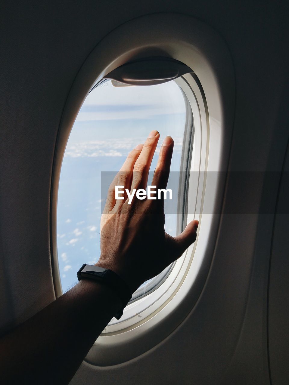 Cropped hand of man reaching airplane window