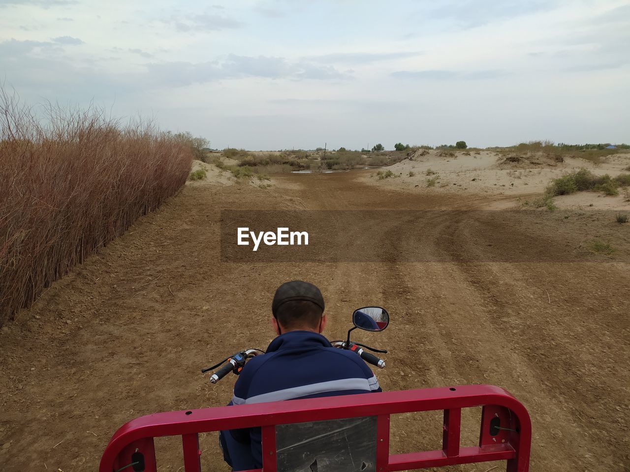 REAR VIEW OF MAN RIDING MOTORCYCLE ON LAND
