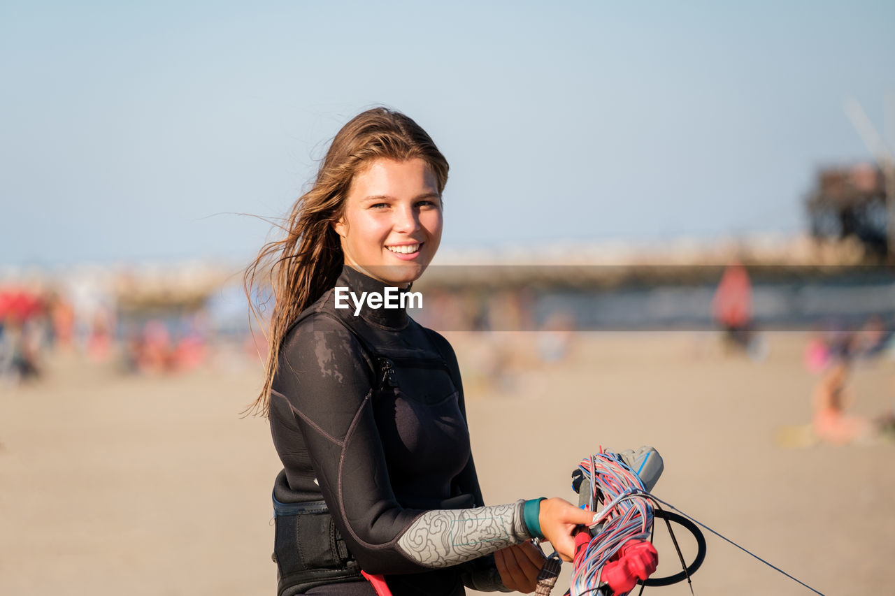 portrait of smiling young woman with dog against clear sky