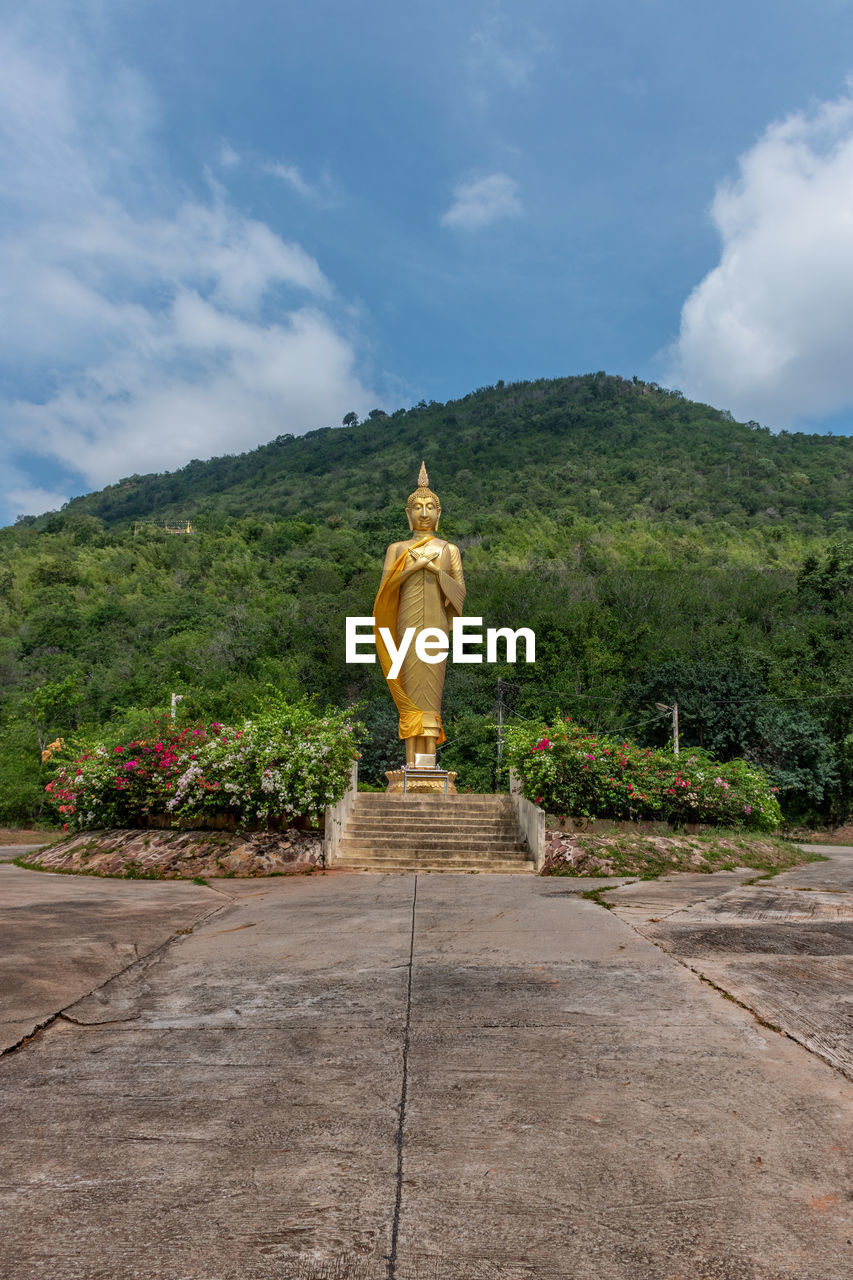 STATUE AMIDST TREES AGAINST SKY