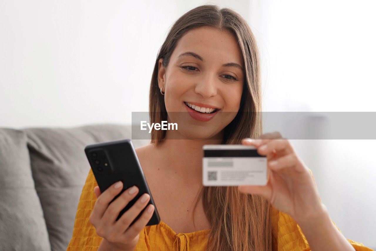 Close-up of hispanic woman reading credit card number for online shopping at home