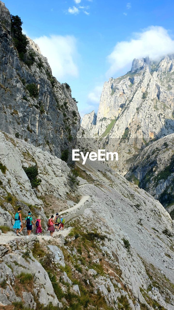 People on walking on pathway against mountains