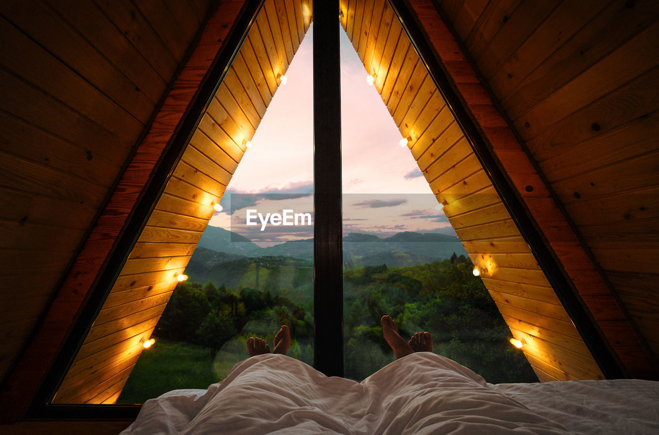 Couple in bed in a-frame cabin looking at sunset on mountain