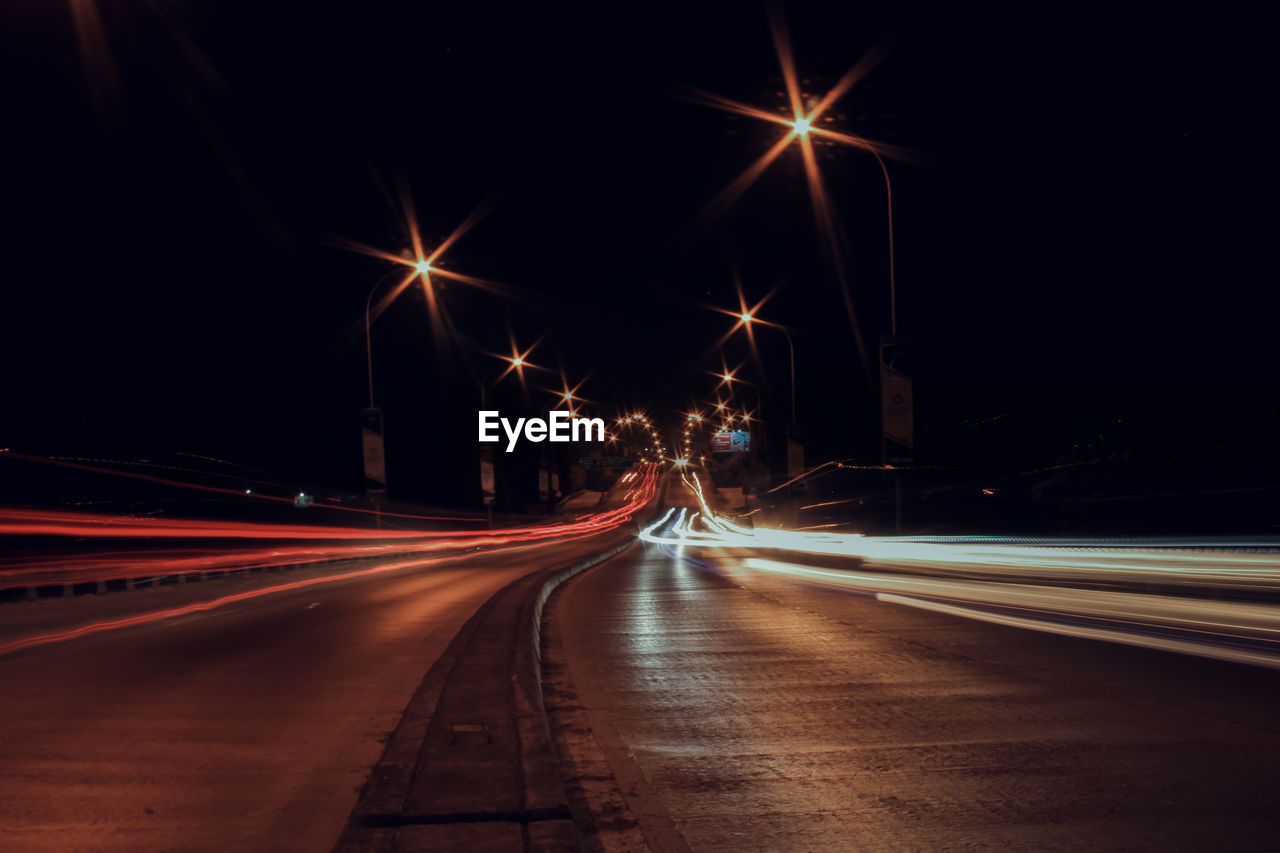 ILLUMINATED LIGHT TRAILS ON STREET AT NIGHT