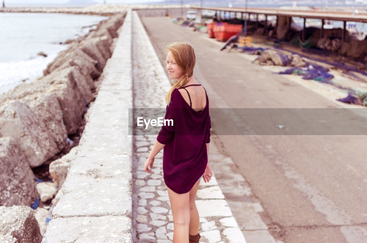 Rear view of woman walking by the beach