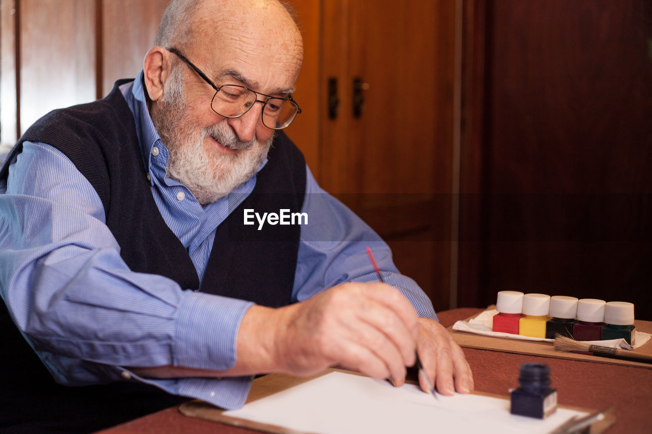 Senior man writing on paper at table