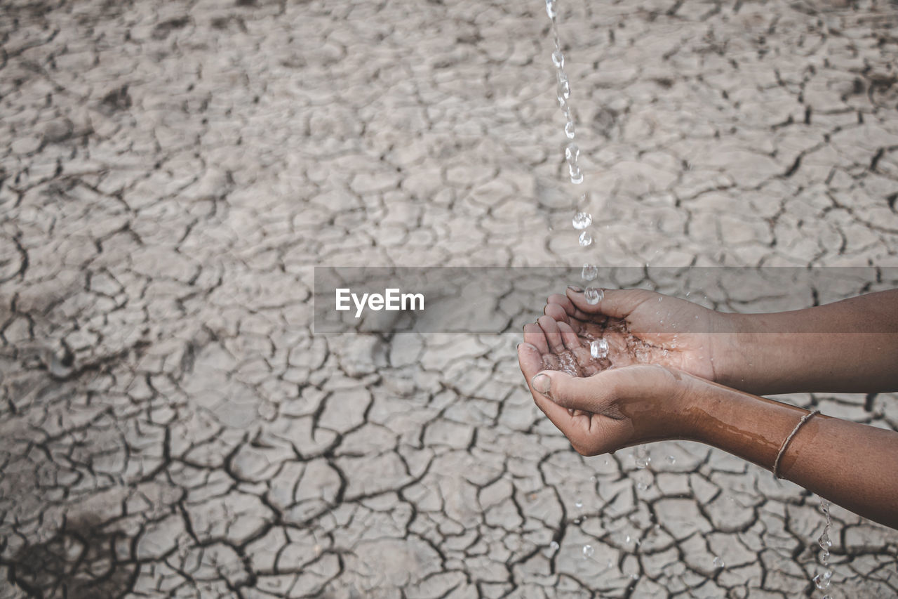 Cropped image of hand holding water against barren land