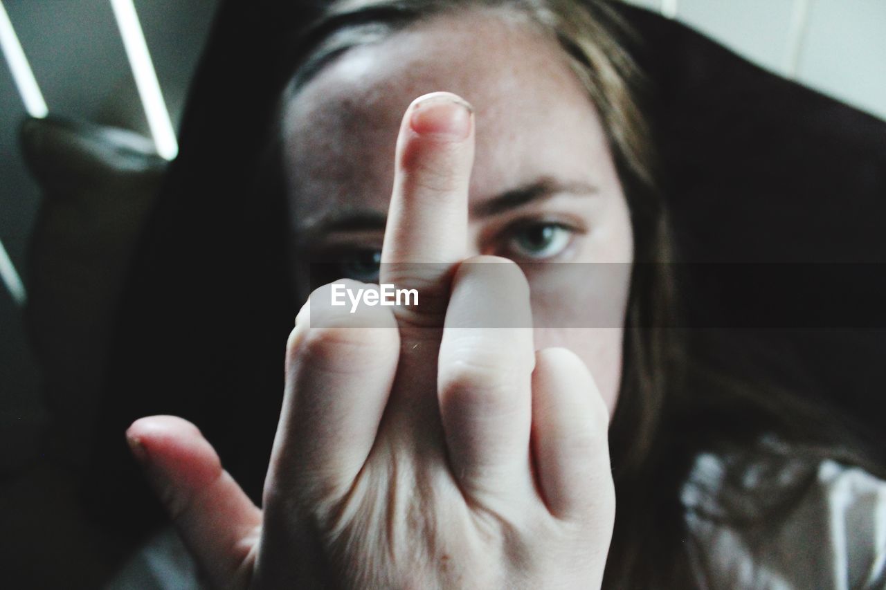 Close-up of woman showing obscene gesture