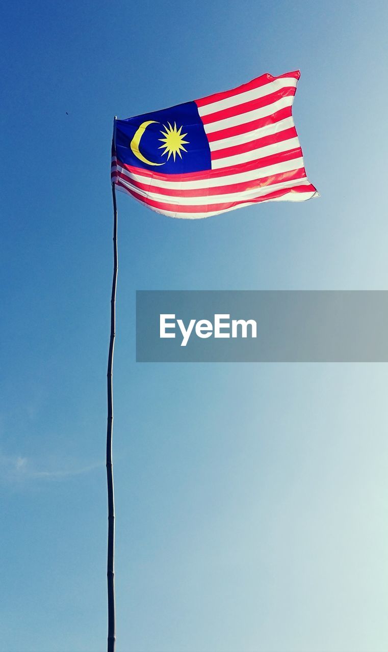 Low angle view of malaysian flag against clear blue sky