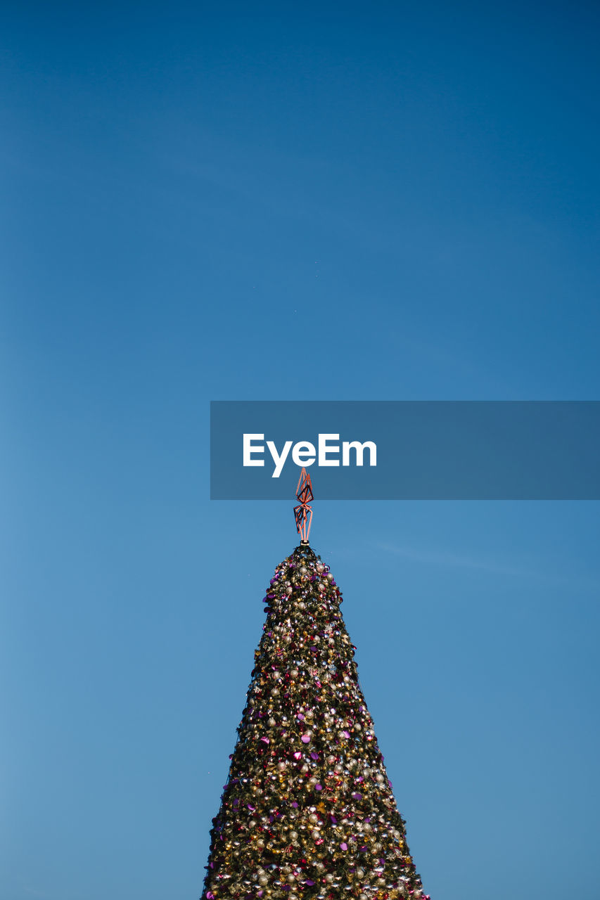 Illuminated christmas tree against blue sky