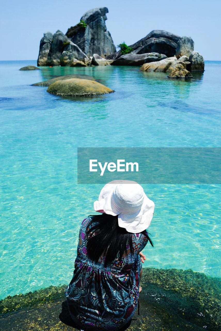 Rear view of woman sitting against sea