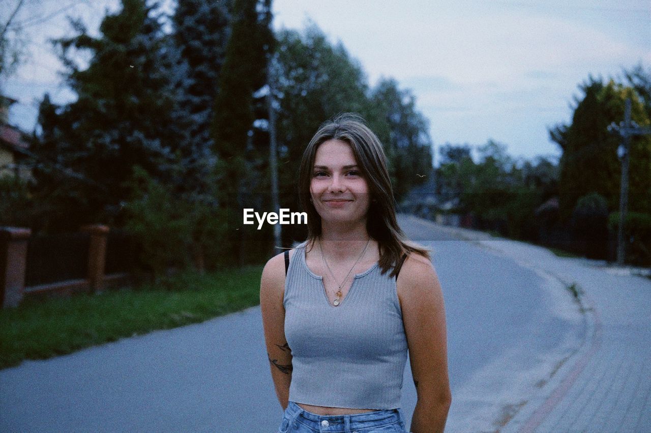 Portrait of young woman standing against trees