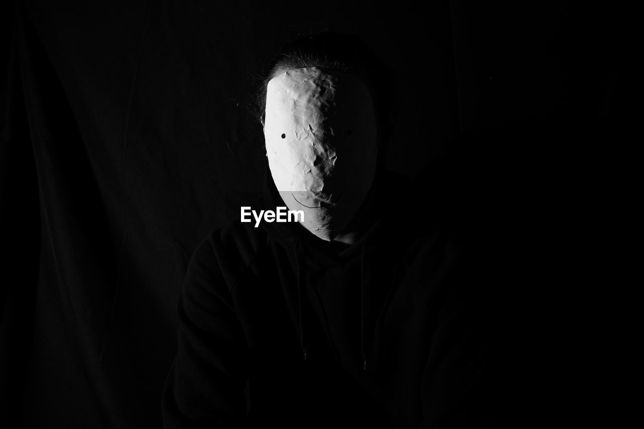 Portrait of man against black background wearing mask