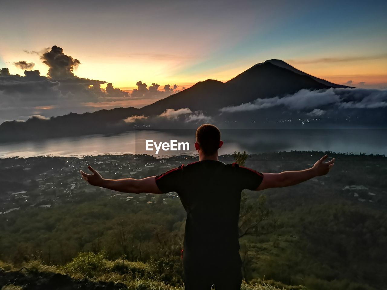 Rear view of man standing on mountain against sky