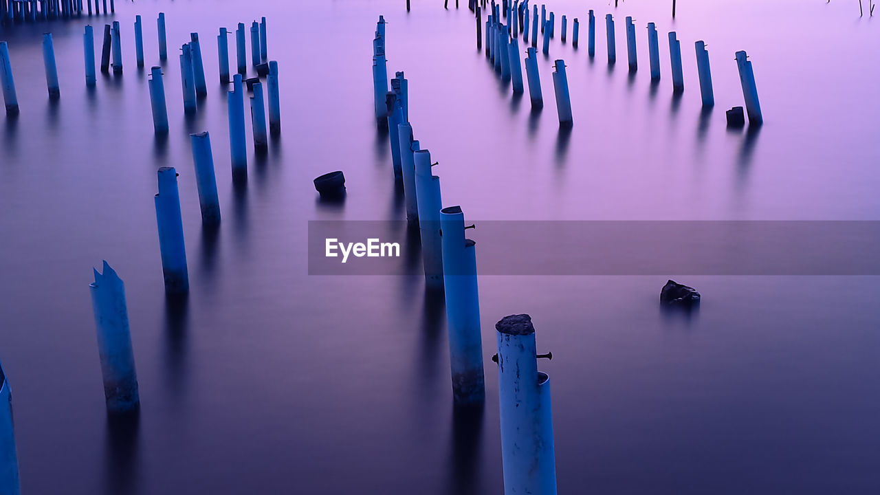 Panoramic view of wooden posts in water at sunset
