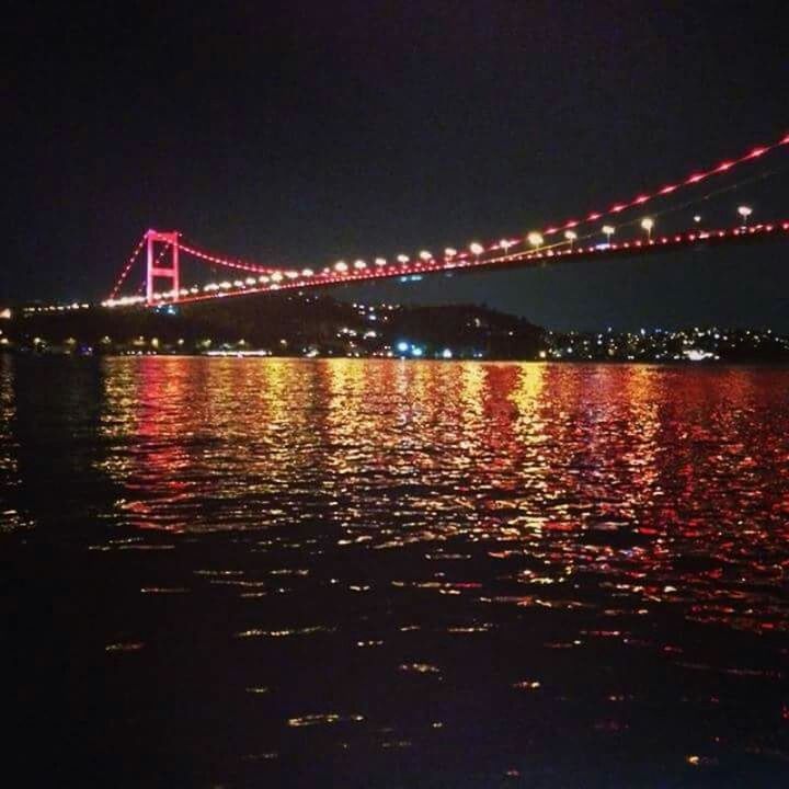 ILLUMINATED BRIDGE OVER RIVER AT NIGHT