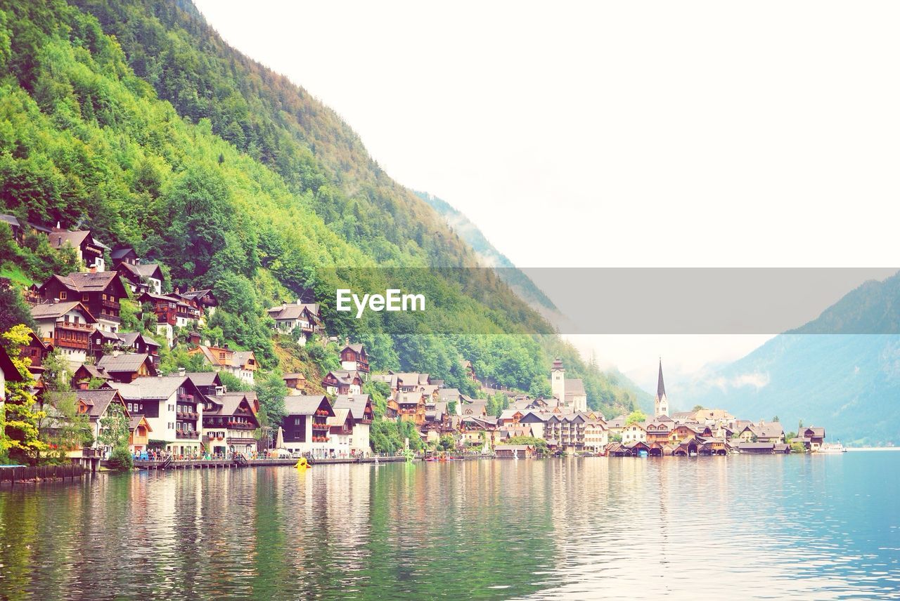 Houses by lake against clear sky