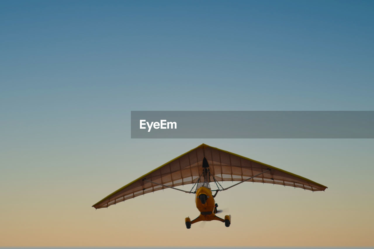 Low angle view of glider against clear sky during sunset