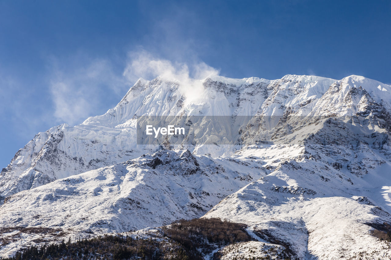 Scenic view of snow mountains against blue sky