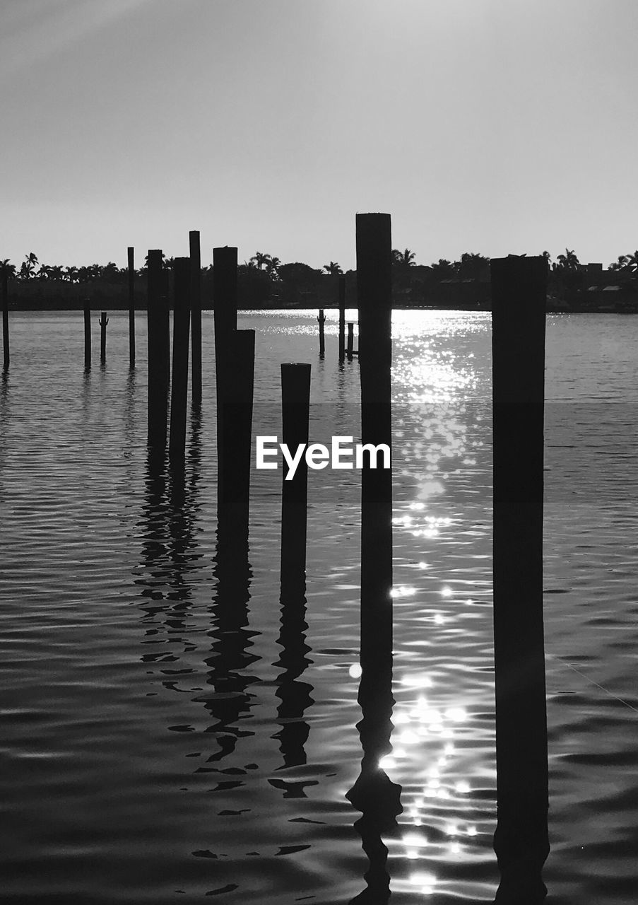 WOODEN POST IN LAKE AGAINST SKY