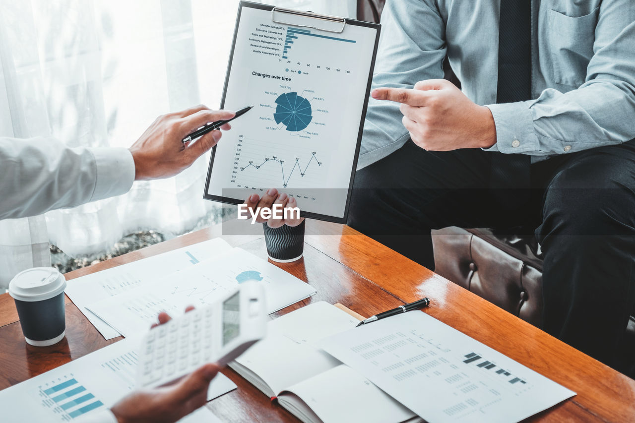 Cropped image of business colleagues gesturing at clipboard