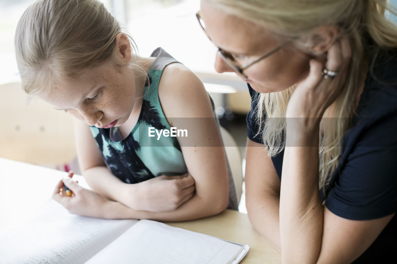 High angle view of girl with teacher at classroom