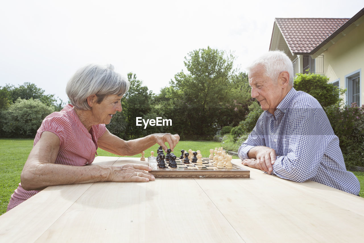 Senior couple playing chess in garden