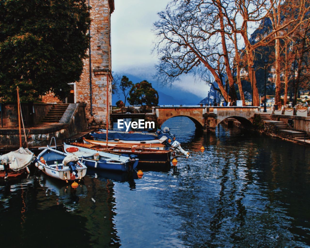 BOATS MOORED IN RIVER AGAINST SKY IN CITY