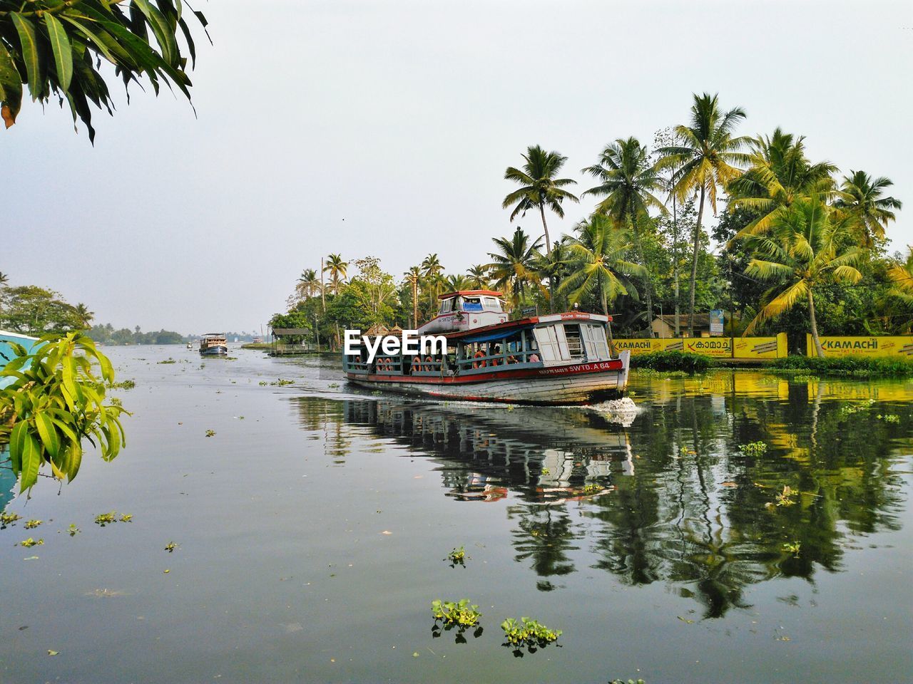 Boat on river by trees against sky