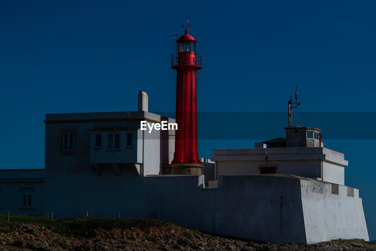 Lighthouse at beach against clear sky