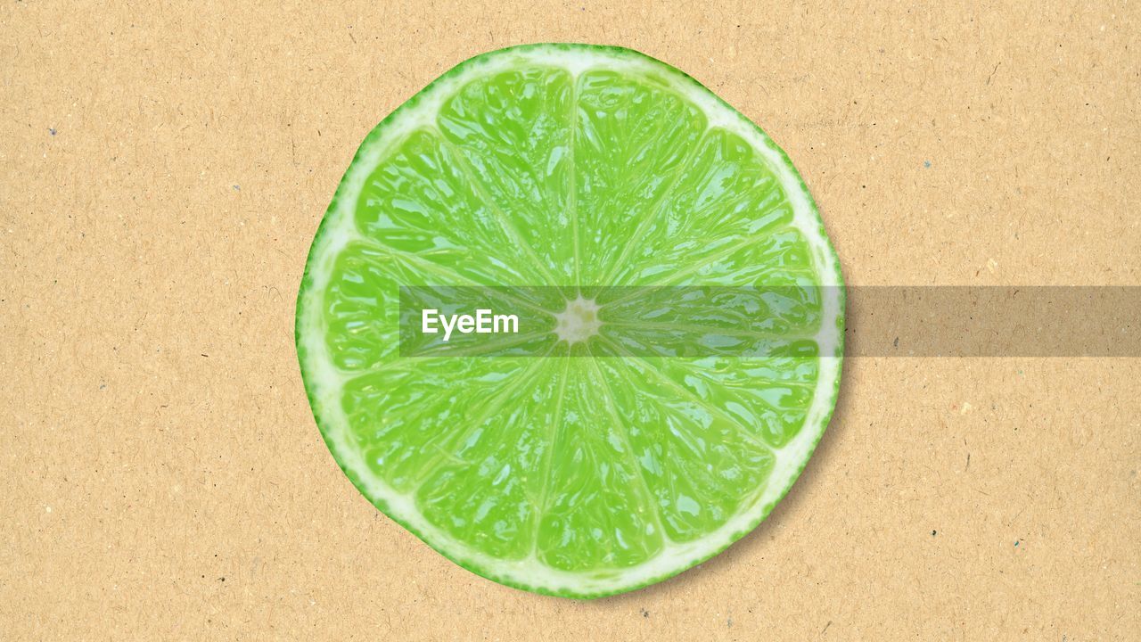 green, healthy eating, leaf, food and drink, fruit, plant, wellbeing, food, no people, freshness, produce, citrus, nature, slice, directly above, citrus fruit, circle, lime, geometric shape, sand, close-up, land, high angle view