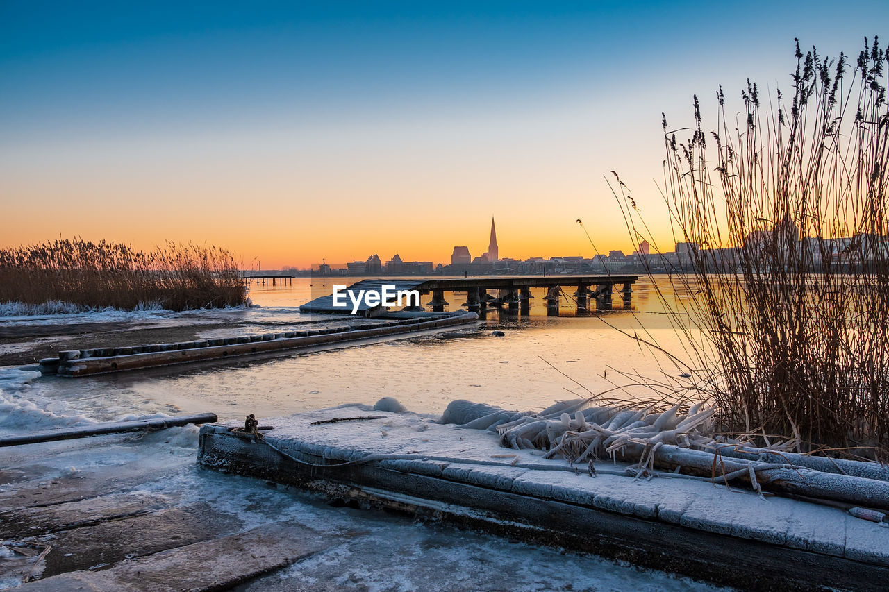 BRIDGE OVER RIVER DURING WINTER AGAINST SKY