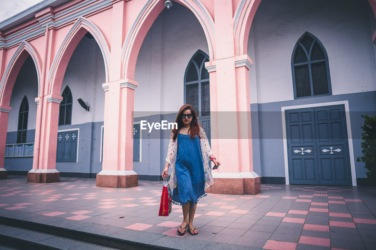 Young woman walking against building