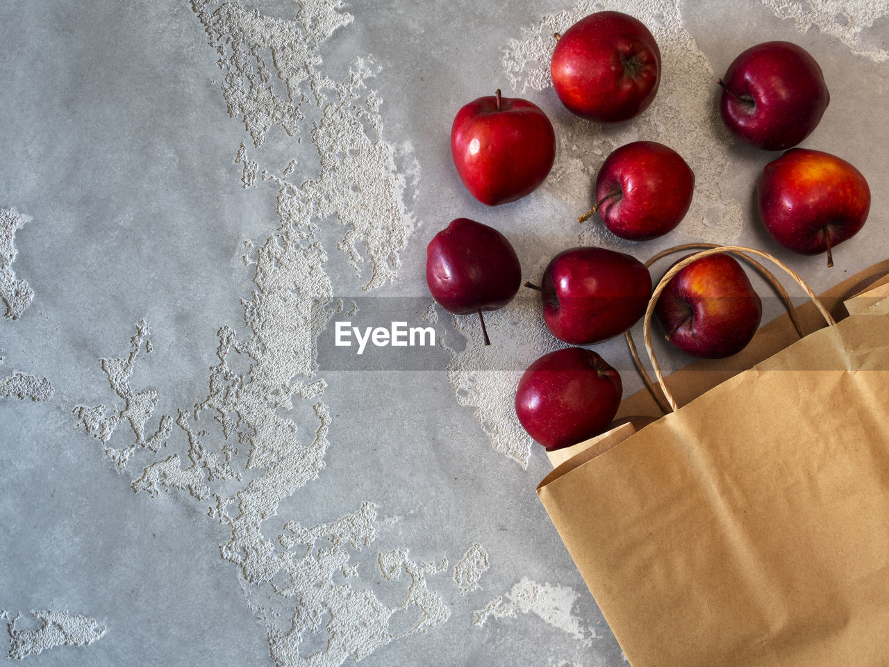 Flat lay photo of paper bag with apples on grey background