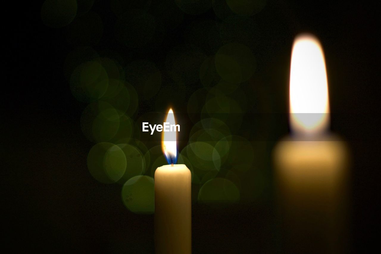 Close-up of illuminated candles in darkroom