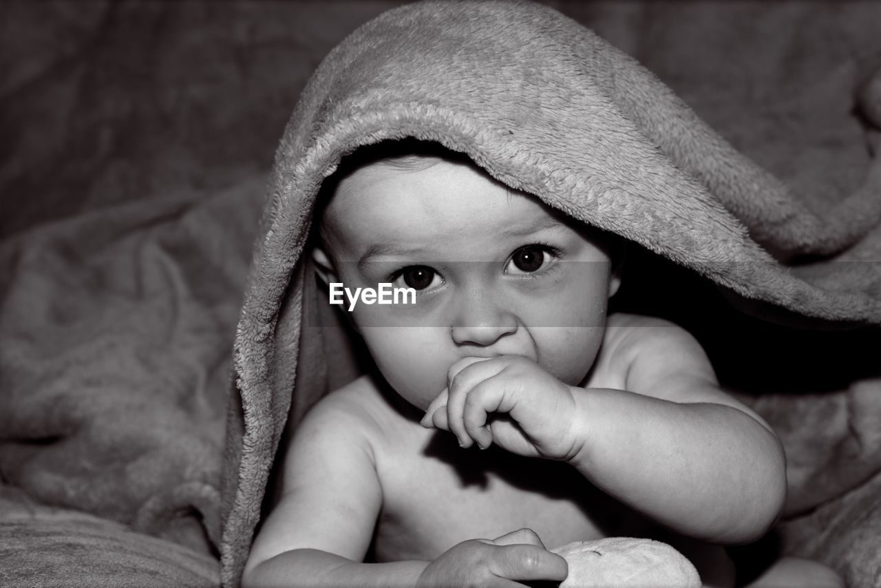 Close-up portrait of cute baby boy wrapped in towel at home