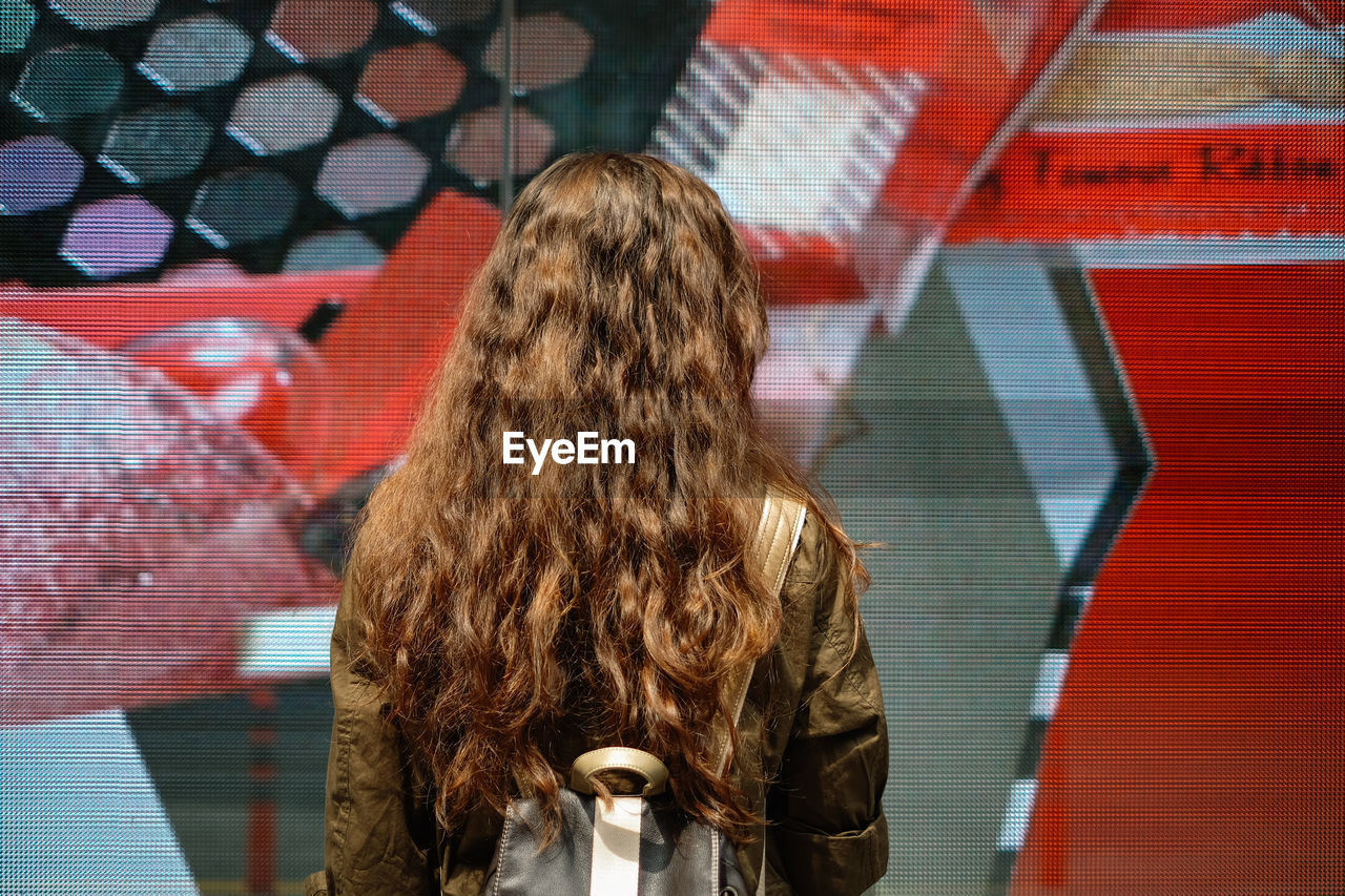 Rear view of young woman with backpack standing on city street