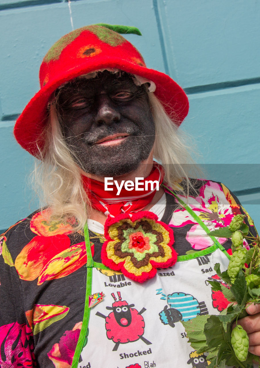 PORTRAIT OF SMILING WOMAN STANDING AGAINST RED WALL