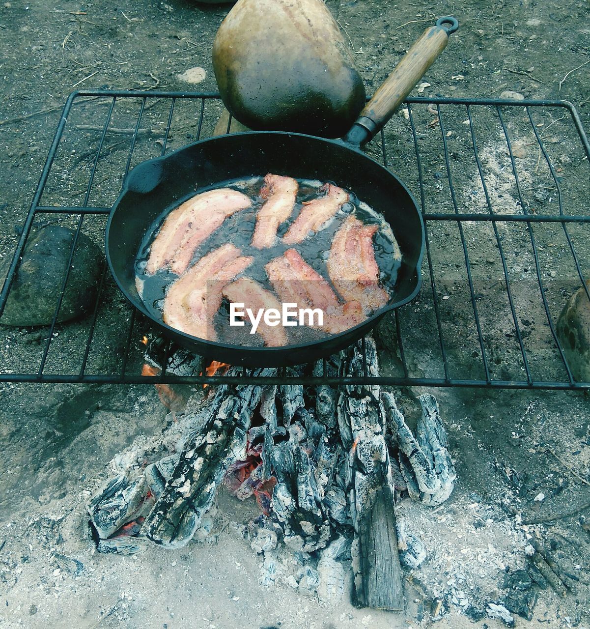 High angle view of meat cooking in container on campfire