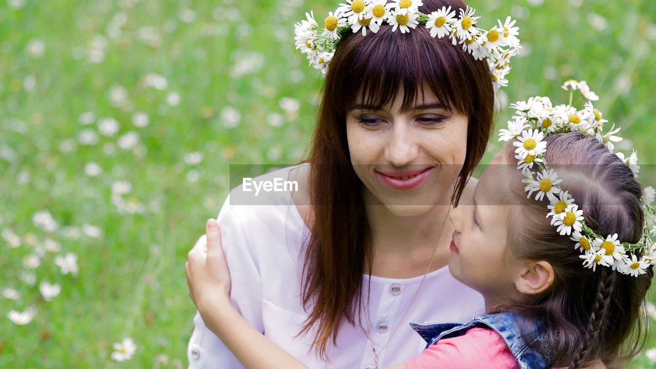 Summer, amidst a chamomile lawn, in the forest, a young woman, a brunette and a girl of seven