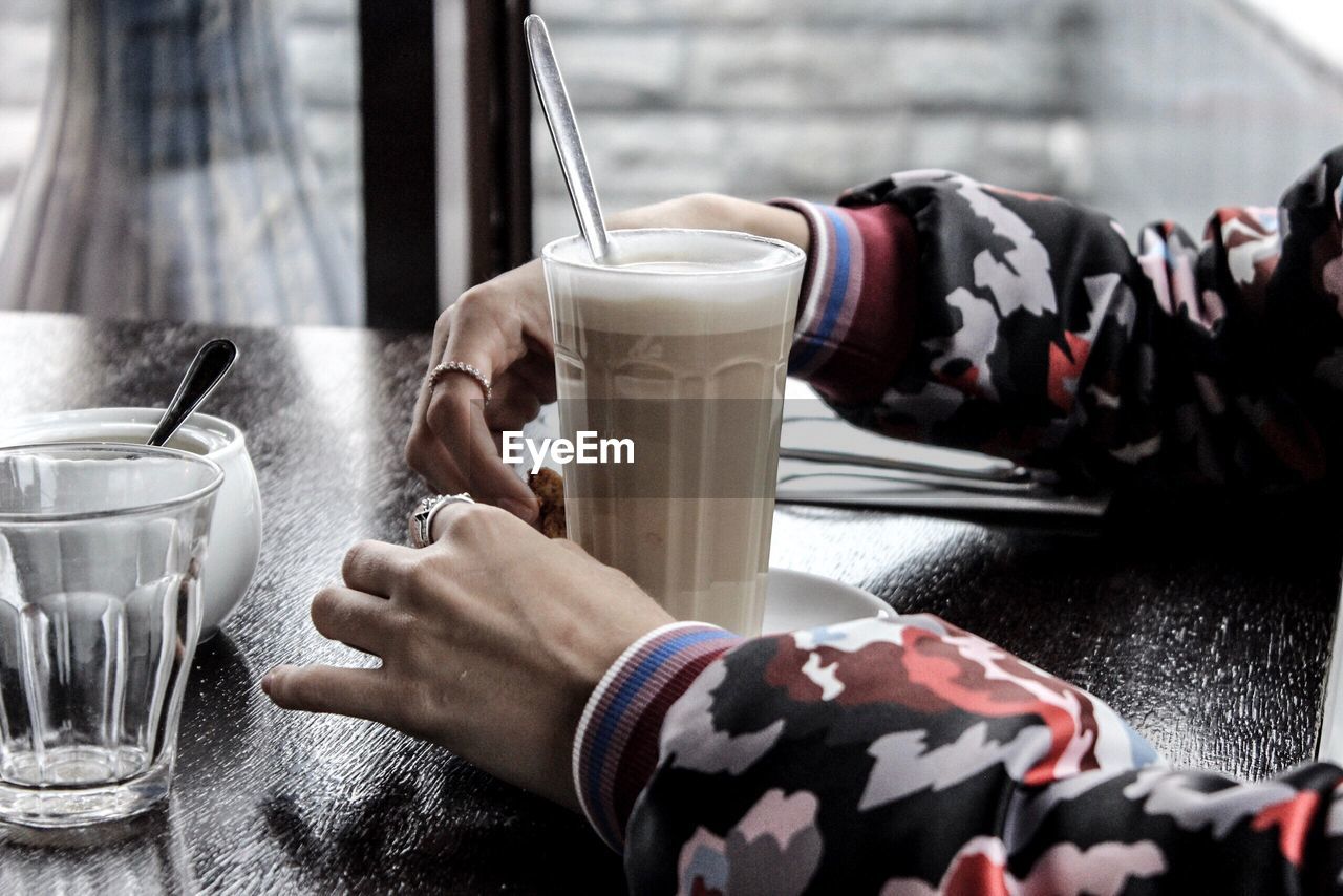 Cropped hands of person with hot chocolate on table in restaurant