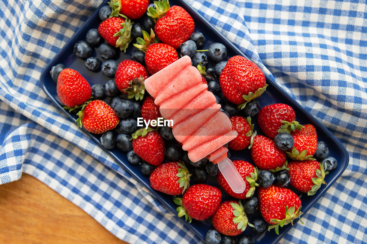 Fresh strawberry and blueberry ice cream lay on fresh strawberry and blueberry.