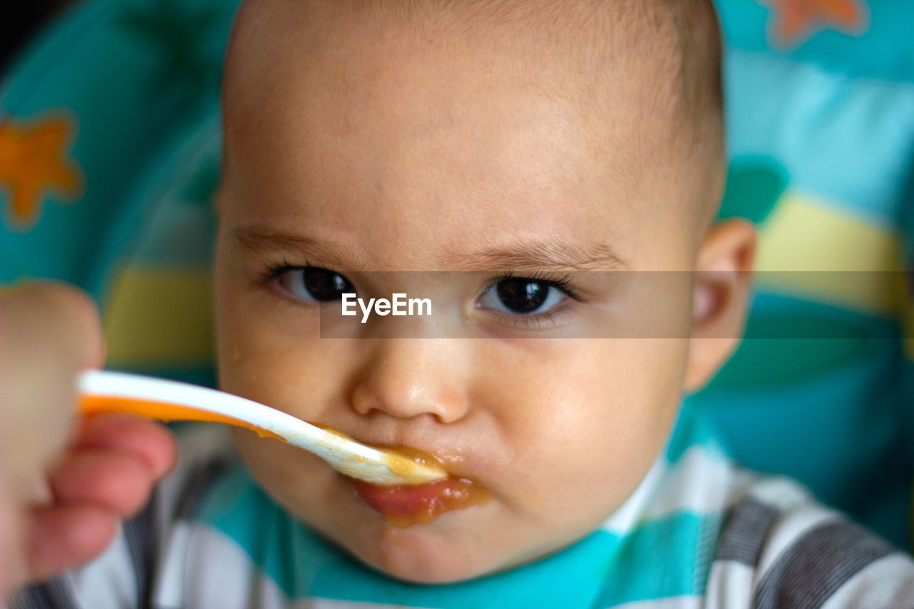 Close-up portrait of cute baby eating